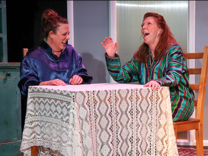 two women laughing at a table
